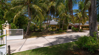 White electric gate and palm-shaded driveway at Jamoon villa, Sandy Lane Estate, Barbados