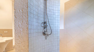 Walk-in mosaic-tiled shower beside a coral-stone wall at Jamoon villa in Barbados