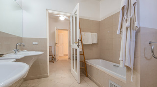 Bathroom with twin basins, a bath tub and robes at Jamoon, Barbados