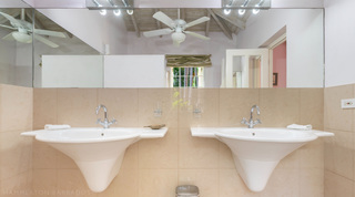 Bathroom with twin pedestal basins and a large mirror at Jamoon villa, Barbados