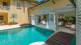 Pool with timber bridge and open living-room doors at Jamoon villa, Sandy Lane Estate, Barbados