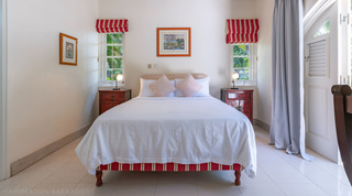 Bedroom with queen bed, red-striped blinds and framed prints at Jamoon villa in Barbados