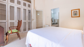 Bedroom with fitted wardrobes and an en-suite glimpse at Jamoon villa, Barbados