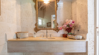 Powder room with floating stone vanity and an ornate gilt mirror at Jamoon, St. James, Barbados