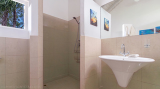 Bathroom with walk-in shower and framed art prints at Jamoon, Barbados