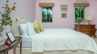 Pink bedroom with twin windows and an antique chest at Jamoon, Barbados