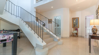 Staircase with wrought-iron balustrade and a games table at Jamoon, Barbados