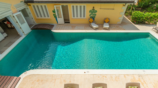 Pool deck with sun loungers and a painted bird mural at Jamoon, holiday villa in St. James, Barbados