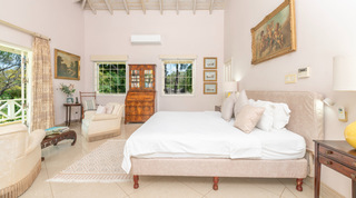 Master bedroom with king bed and French doors to a garden balcony at Jamoon villa, Barbados
