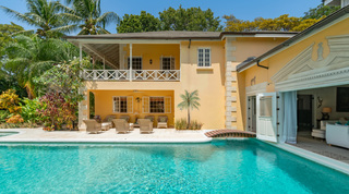 Poolside covered terrace with wicker seating below the balcony at Jamoon, Sandy Lane villa, Barbados