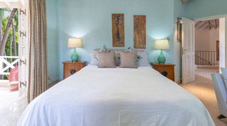 Turquoise bedroom with white bed, twin lamps and antique wall panels at Jamoon, Barbados