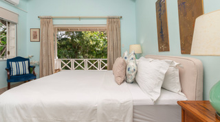 Turquoise bedroom with king bed and balcony doors to greenery at Jamoon villa in Barbados