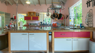 Kitchen island with a hanging pan rack above granite worktops at Jamoon villa, Sandy Lane, Barbados