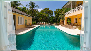 Pool framed through open doors and curtains at Jamoon villa, Barbados