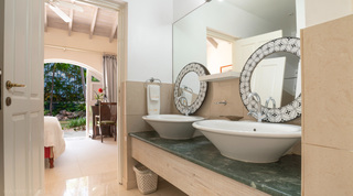 Bathroom with twin vessel basins and patterned round mirrors at Jamoon villa in Barbados