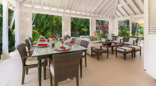 Covered terrace dining and lounge behind white lattice screens at Jamoon villa rental, St. James, Barbados