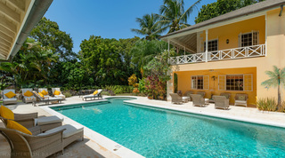 Pool flanked by wicker loungers and palms at Jamoon, fully staffed holiday villa in St. James, Barbados