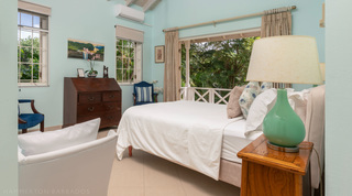 Turquoise bedroom with antique chest and balcony doors at Jamoon, Barbados