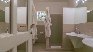 Green bathroom with twin basins and a walk-in shower at Jamoon villa in Barbados