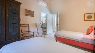 Twin room with a painted antique armoire and en-suite glimpse at Jamoon, Barbados