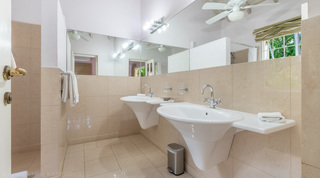 Bathroom with twin wall basins, mirror and ceiling fan at Jamoon villa in Barbados