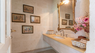 Powder room with stone vanity, gilt mirror and equestrian prints at Jamoon villa in Barbados