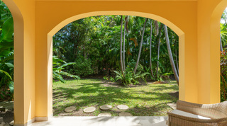 Arched terrace opening onto a stepping-stone garden path at Jamoon villa in Barbados