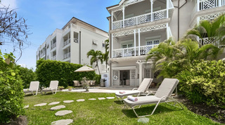 Garden sun loungers and a barbecue below the fretwork balconies at Fathom's End, a villa rental in Barbados
