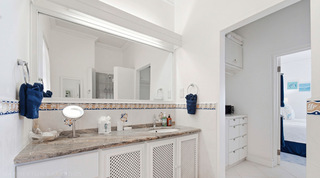 Shell-motif border tiles and navy towels in a Fathom's End shower room, Barbados