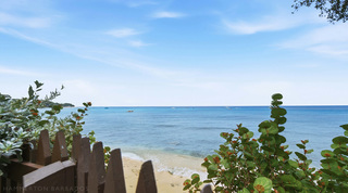 View over the private beach gate to the calm sea and moored boats at Fathom's End, Paynes Bay, Barbados
