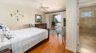 Seahorse wall art and a coral-print rug in a bedroom at Monkey Hill in Barbados, opening onto the pool terrace and sea