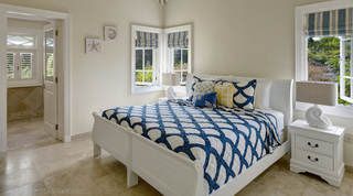 Two white sleigh beds made up as one under a navy scallop quilt with nautilus-shell lamps at Monkey Hill in Barbados