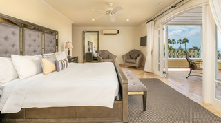 Grey tufted headboard with mirrored trim and doors to a palm and sea-view balcony in a Monkey Hill bedroom, Barbados