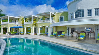 Pool and lime-green loungers below the pale green facade and white rotunda of Monkey Hill, luxury villa in Barbados
