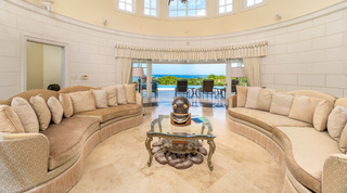 Curved fringed sofas either side of a diving helmet on a glass table in the rotunda living room, Monkey Hill, Barbados