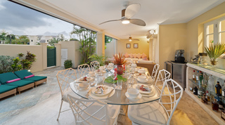 Glass dining table laid for dinner beside the coral stone bar at Mullins Bay 13 Coco villa, Barbados