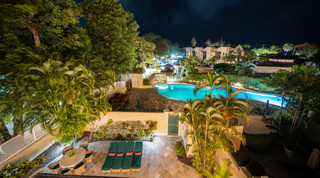 Green sun loungers and patio dining with the communal pool floodlit beyond, Mullins Bay 13 Coco villa, Barbados