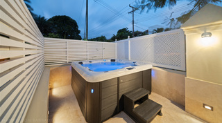Hot tub lit blue behind white slatted and latticed screens, Mullins Bay 13 Coco villa in Barbados