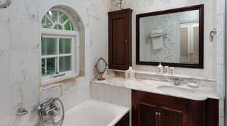 Marble bathroom with a bath under an arched window at Mullins Bay Villa – Twin Palms, luxury villa in Barbados