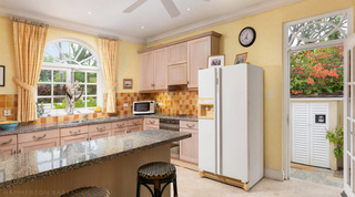 Kitchen of Mullins Bay Villa – Twin Palms, Barbados, with a granite breakfast bar and an open door framing bougainvillea