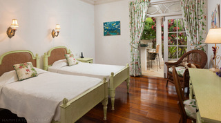 Twin beds with cane headboards beside doors to the terrace bar in a guest room at Mullins Bay Villa – Twin Palms, Barbados
