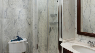 Glass shower and carved wood mirror in a marble shower room at Mullins Bay Villa – Twin Palms, Barbados holiday villa