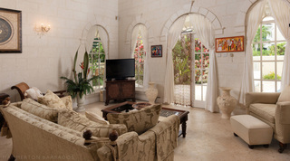 Living room with arched windows, white curtains and French doors to the garden at Mullins Bay Villa – Twin Palms, Barbados