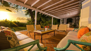 Covered terrace lounge with floral cushioned sofas at sunset over the sea at Mullins Mill, luxury villa in Barbados