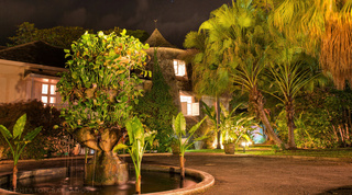 Floodlit sugar mill tower and gardens at night with the planter fountain in front at Mullins Mill, Barbados