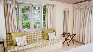 Cushioned window seat with a luggage rack and framed mirror in a bedroom at Mullins Mill, Barbados