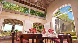 Covered dining verandah laid with red napkins under arched openings at Mullins Mill, villa rental in Barbados