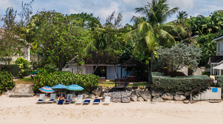 Mullins Mill beach house among palms with parasols and sun loungers on the sand at Gibbs Beach, Barbados