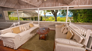 Covered verandah lounge with cream sofas and sea views through the trees at Mullins Mill villa, Barbados