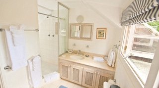 Bathroom with a glass walk-in shower and stone-topped vanity with woven doors at Mullins Mill, Barbados
